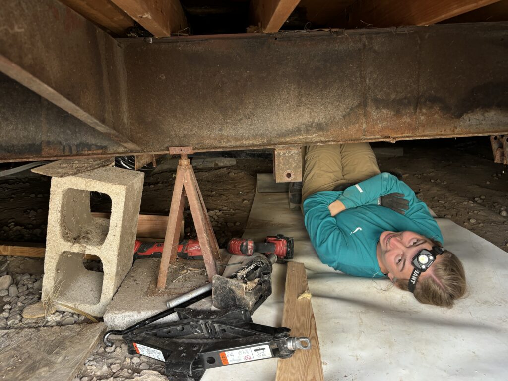Hannah Lehman works underneath a mobile home.