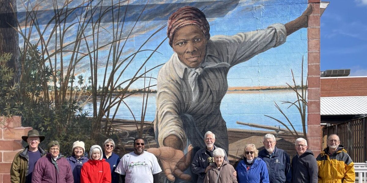 The pilgrims stand before the Harriet Tubman Mural on an exterior wall of the Harriet Tubman Museum and Educational Center in Cambridge, Maryland. Artist Michael Rosato designed and painted the mural, which was completed in 2019. From left to right: Paul Knapke, JoAnn Knapke, Julie Hart, Rachel Gratz, Krisann Applegate, Alex Green (Harriett Tubman Tours tour guide), Philip Hart, Katherine Bauman, Marlene Suter, Scott Applegate, Conrad Gratz. Photo by Arloa Bontrager.