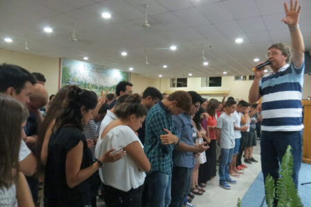 ​Pastor Daniel Oyanguren prays for youth and young adults who came forward in response to a missionary call at the January assembly of the Iglesia Evangélica Menonita Argentina (IEMA) in Choele Choel. The IEMA sends missionary church planters to share God's good news throughout the country. Photo by Linda Shelly.