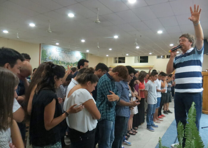 ​Pastor Daniel Oyanguren prays for youth and young adults who came forward in response to a missionary call at the January assembly of the Iglesia Evangélica Menonita Argentina (IEMA) in Choele Choel. The IEMA sends missionary church planters to share God's good news throughout the country. Photo by Linda Shelly.