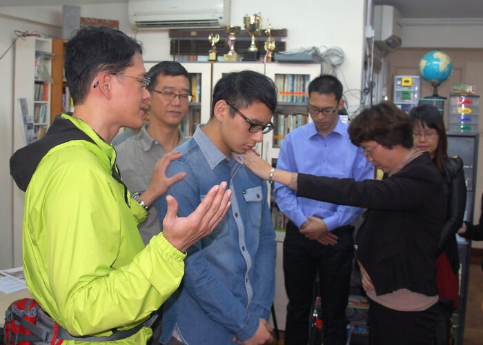 Exchange participants praying for a seminary student from Agape Mennonite Church in Hong Kong. Photo by George Veith. Download full resolution image.