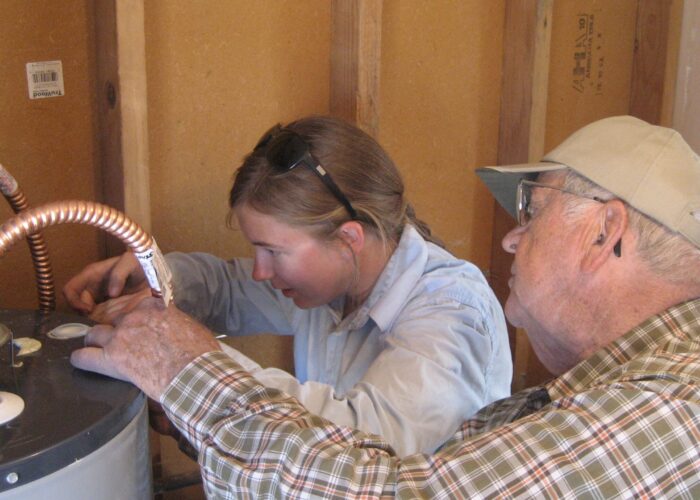 Walter Good and Miriam Regier work together to repair a water heater