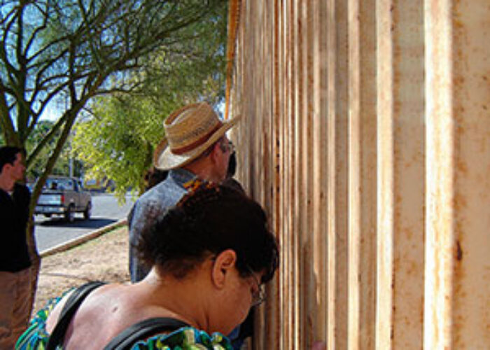 Members of a tour to the Mexico-United States border pray at the wall dividing the two countries.