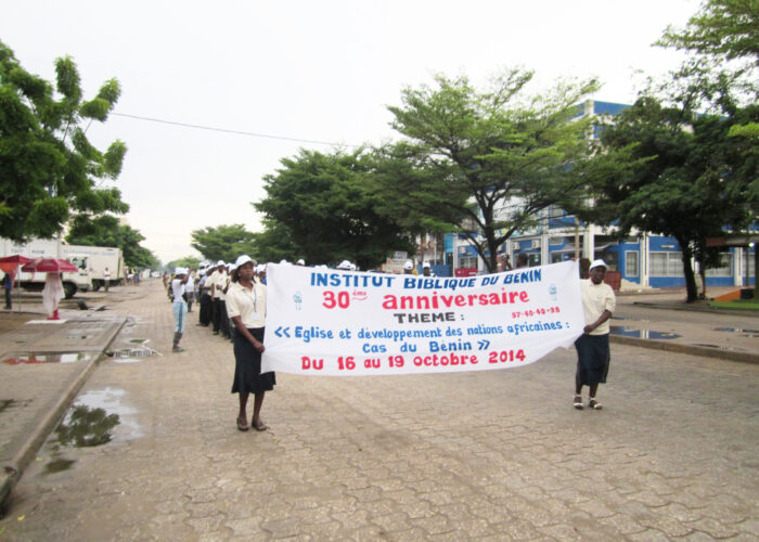 Solange Akpo and Delphine Worou lead the Benin Bible Institute procession through the streets of Cotonou to the rhythms of a brass band