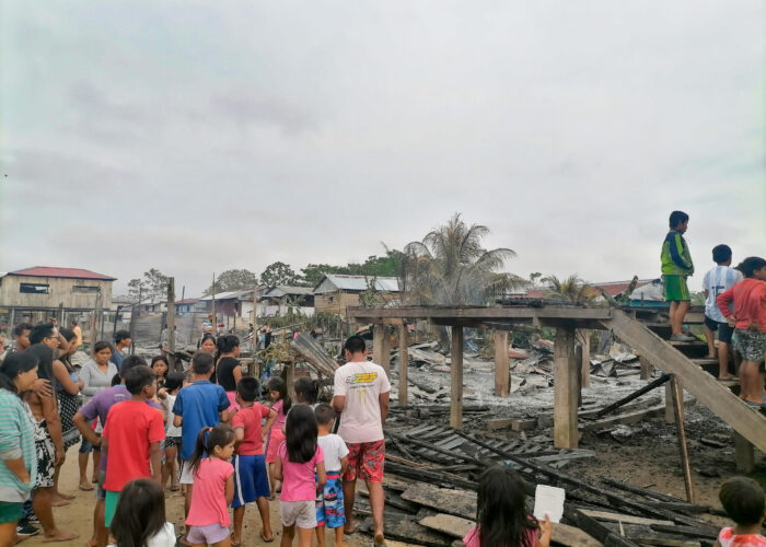 ​Adults and children living on Isla Iquitos in Peru survey the damage at the site where their church and five houses burned to the ground the night of August 29. Children stand on the stairs that once led to their space for worship and learning. Photo by Juan Carlos Moreno.