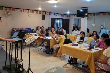 Jonah Yang (left, on stage) leads a session on leadership training during a Compassionate Care retreat in Southeast Asia. Photo by Memee Yang.