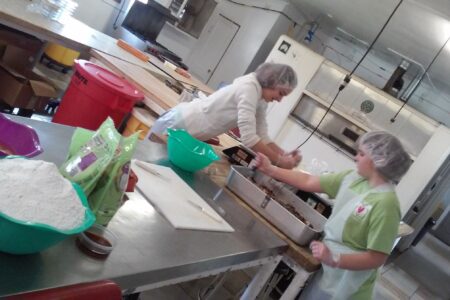 ​Alina and Marta Bergstresser help mix batter for date-nut bread in the Koinonia Farm bakery during their SOOP term in April 2019 in Americus