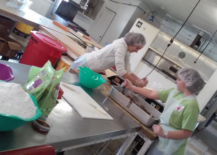 ​Alina and Marta Bergstresser help mix batter for date-nut bread in the Koinonia Farm bakery during their SOOP term in April 2019 in Americus