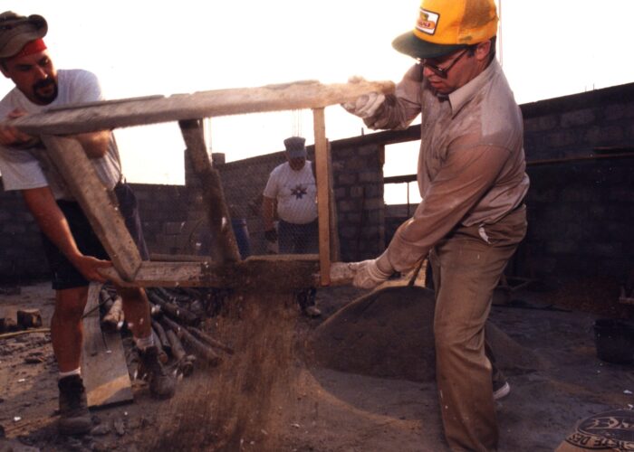 After mixing sand and cement by hand and sifting out rocks and other debris