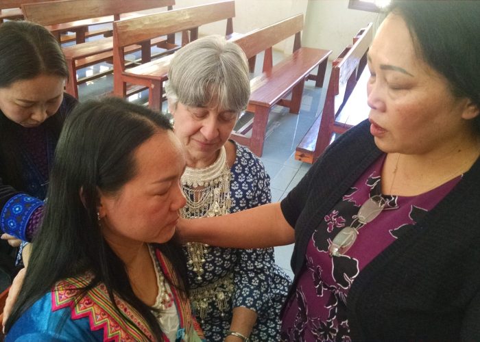 ​Memee Yang (right) prays for Song Vang at the Thailand Sister Care seminar held Jan. 20-22