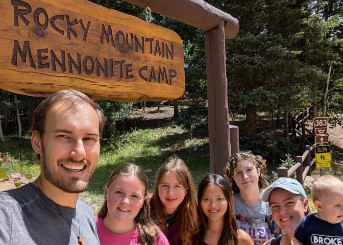 The 2024-25 Colorado Springs unit poses in front of the Rocky Mountain Mennonite Camp entrance sign. The camp is a Mission Network partner and placement site. From left: Christian Stoltzfus (unit leader), Elizabeth Daudey, Alea Sagert, Hannah Smith, Sadie Sherman, Leigha Stoltzfus (unit leader) with daughter Naomi. Photo by Christian Stoltzfus.