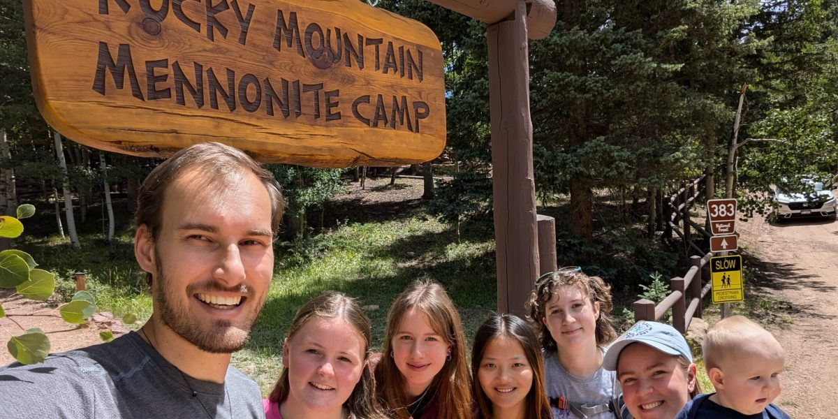 The 2024-25 Colorado Springs unit poses in front of the Rocky Mountain Mennonite Camp entrance sign. The camp is a Mission Network partner and placement site. From left: Christian Stoltzfus (unit leader), Elizabeth Daudey, Alea Sagert, Hannah Smith, Sadie Sherman, Leigha Stoltzfus (unit leader) with daughter Naomi. Photo by Christian Stoltzfus.