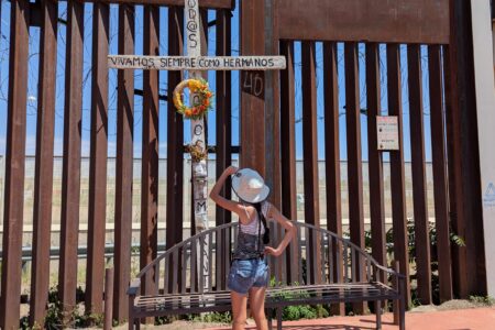 Mya Cook looks up at a cross placed on the border wall. Photo by Jonathan Wenger.