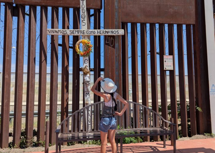 Mya Cook looks up at a cross placed on the border wall. Photo by Jonathan Wenger.