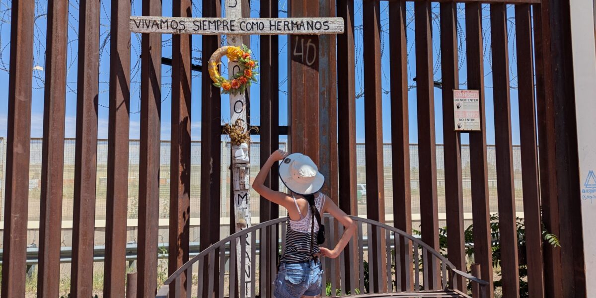 Mya Cook looks up at a cross placed on the border wall. Photo by Jonathan Wenger.
