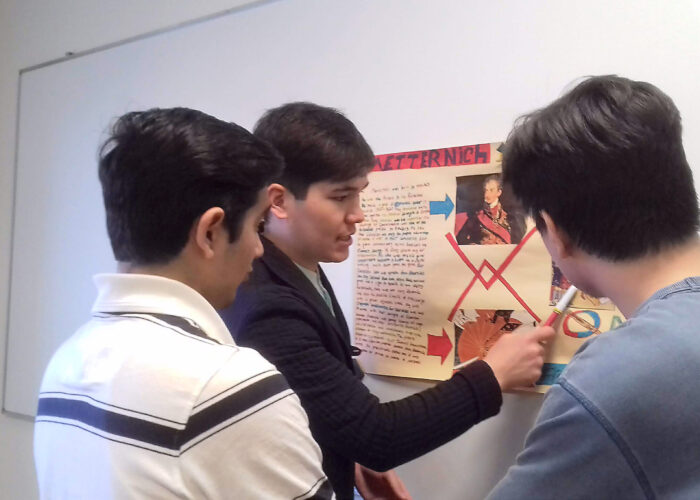 ​This LCC University student from Uzbekistan is explaining his European history poster to his classmates from Afghanistan. (Names withheld for privacy.) Photographer: Robin Gingerich.