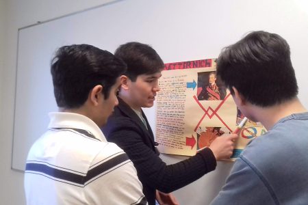 ​This LCC University student from Uzbekistan is explaining his European history poster to his classmates from Afghanistan. (Names withheld for privacy.) Photographer: Robin Gingerich.