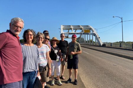 Members of Community Mennonite Church's Just Peace Pilgrimage group stand before the Edmund Pettus Bridge in Selma, Alabama. From left to right: Art Stoltzfus, Meribeth Kraybill, Betty Shenk, Rene Hostetter, Isaac Witmer, Ruth Zimmerman, Keaton Shenk, and Earl Zimmerman. Photo provided.